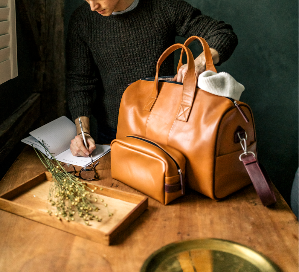 Model writes in a journal while traveling with luxury leather bags