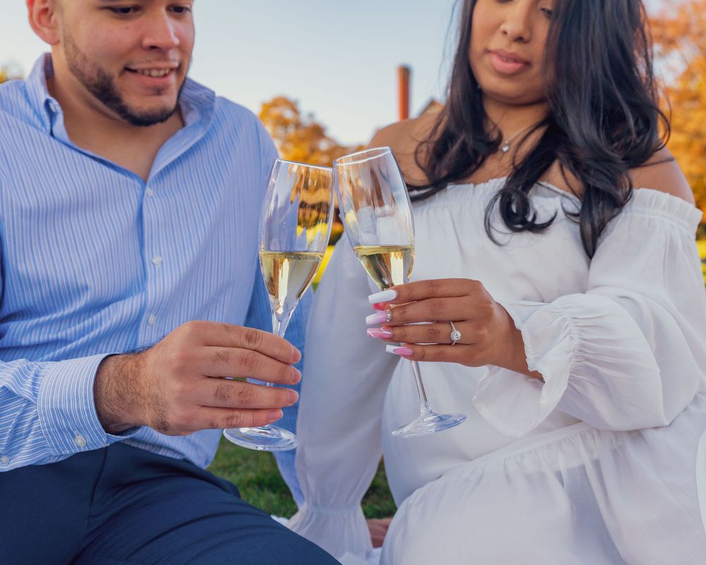 Two people toasting with champagne glasses outdoors while enjoying a sunny day together.