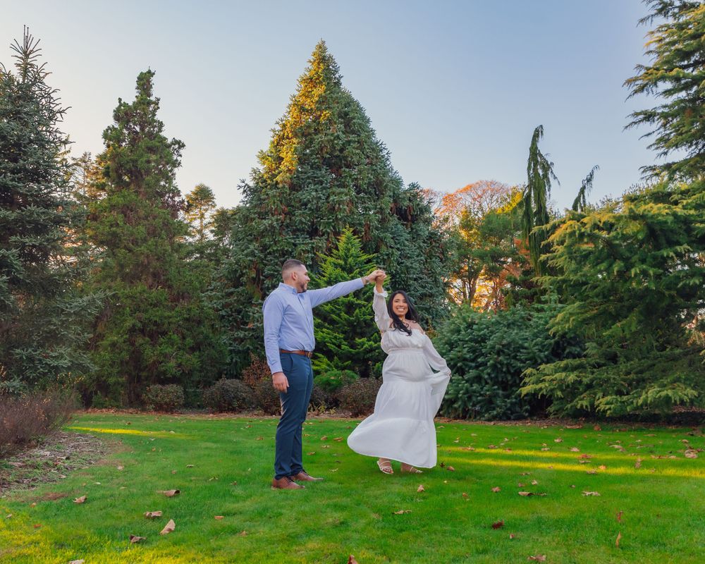 Dancing couple in a garden setting with evergreen trees and mountains visible in the background.
