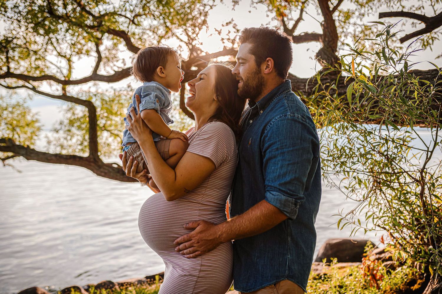 Future maman au bord de l'eau, au couché du soleil qui joue avec son enfant et son mari