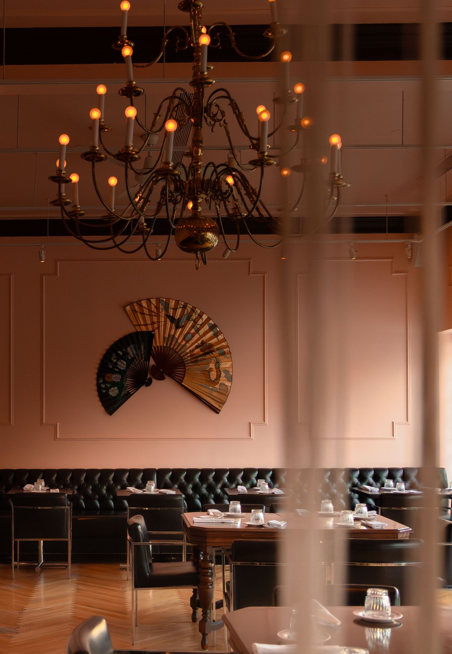 Elegant restaurant interior with chandeliers and black leather booth seating.