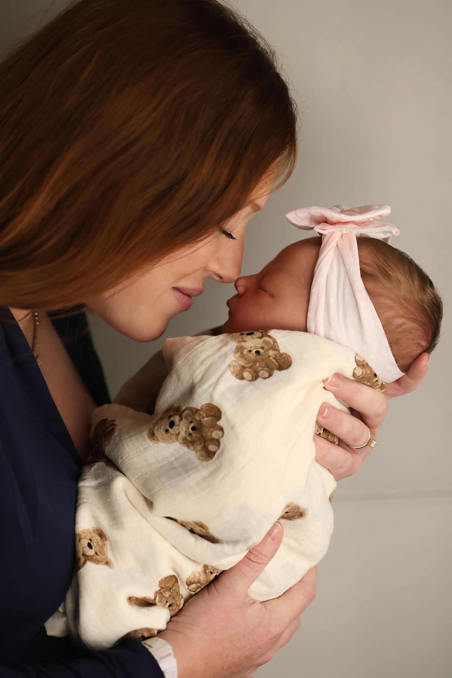 Close-up of gentle hands touching a sleeping newborn's face.
