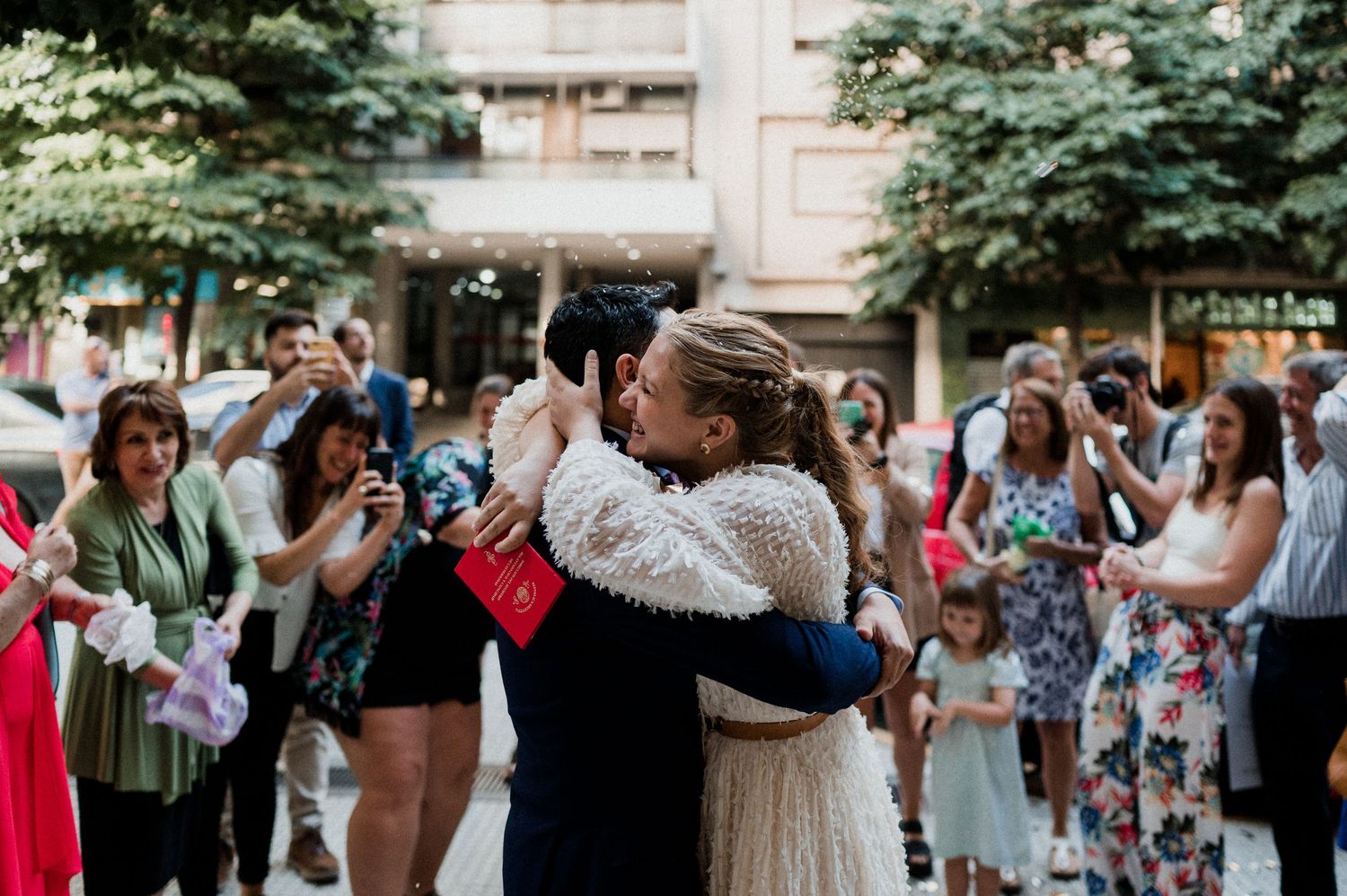 A couple shares their first dance surrounded by celebrating guests at an outdoor wedding.