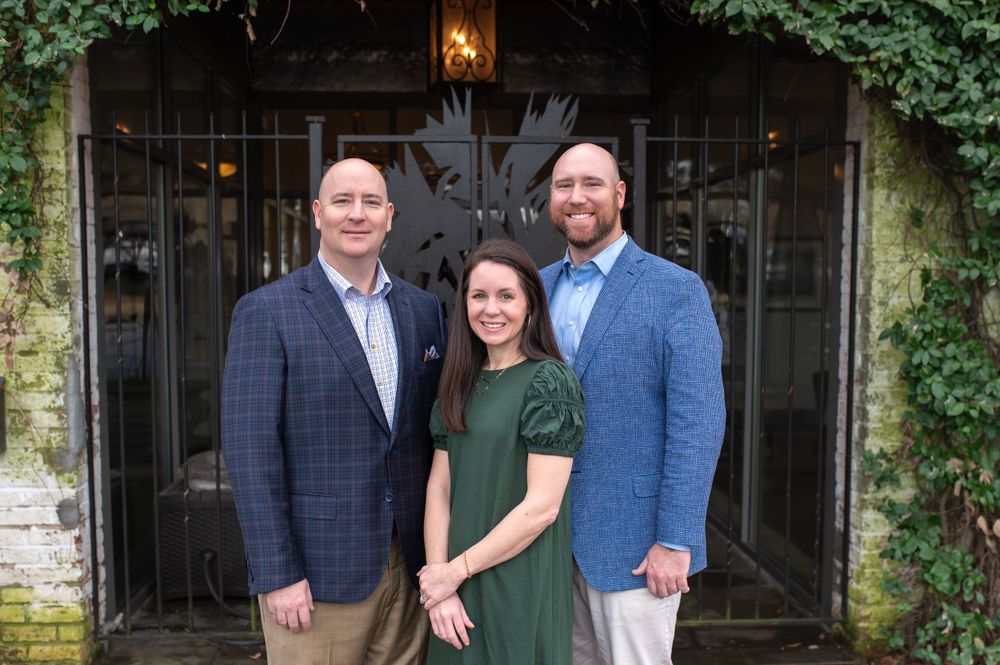 Business team poses together outside historic building with ivy-covered walls.