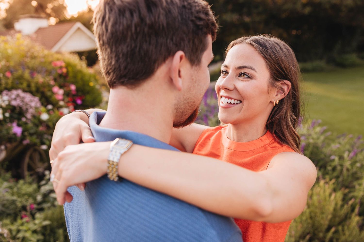 Two people share a joyful moment together outdoors with soft bokeh greenery in the background.