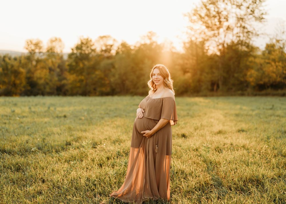A glowing sunset maternity portrait in a brown dress amidst a golden field.