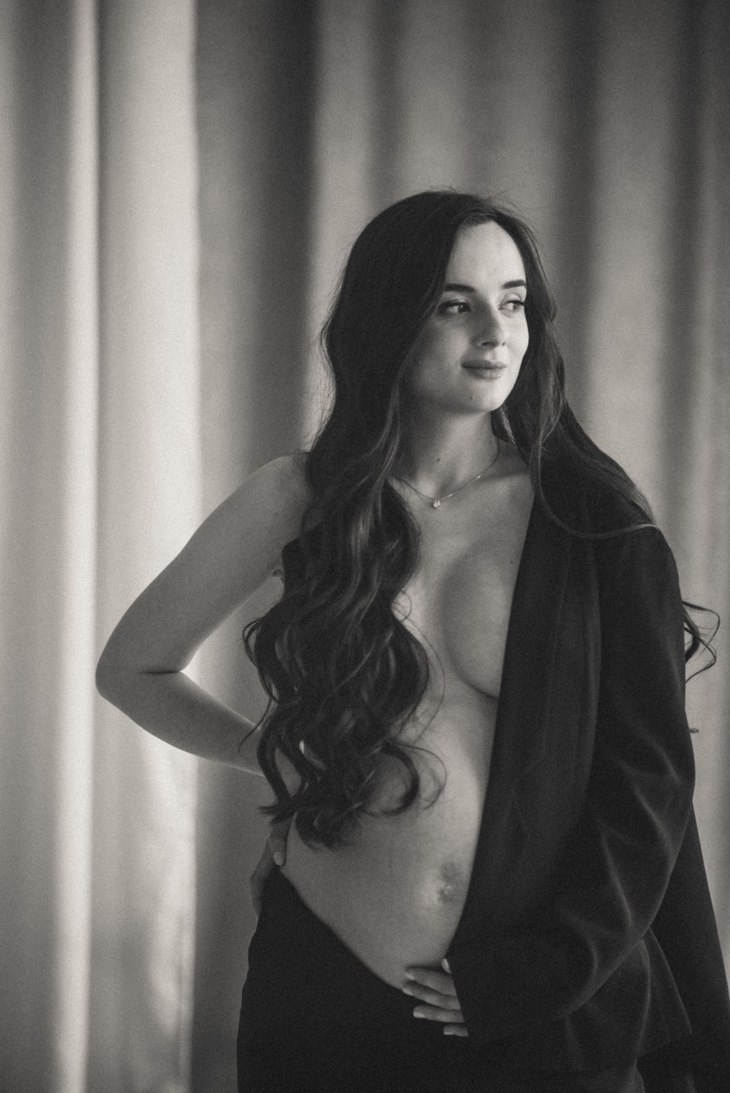 Stylish cinematic portrait of a pregnant woman in a men's black suit.