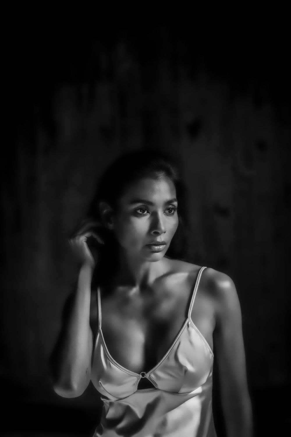 Dramatic black and white portrait with moody lighting and satin clothing.