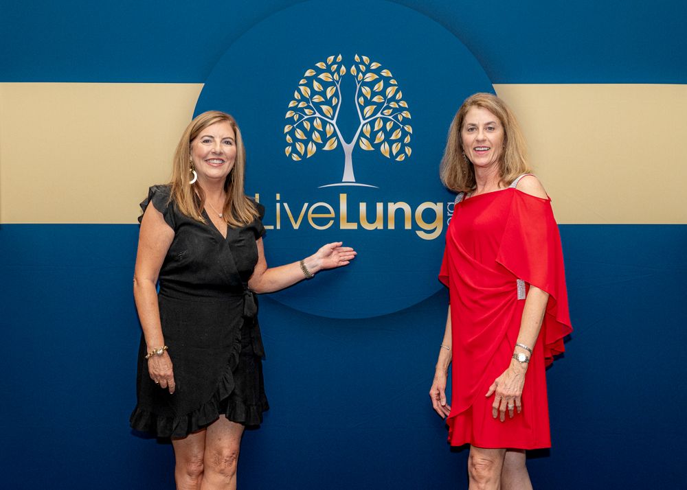 Attendees pose at a LiveLung charity event in front of a branded blue backdrop.