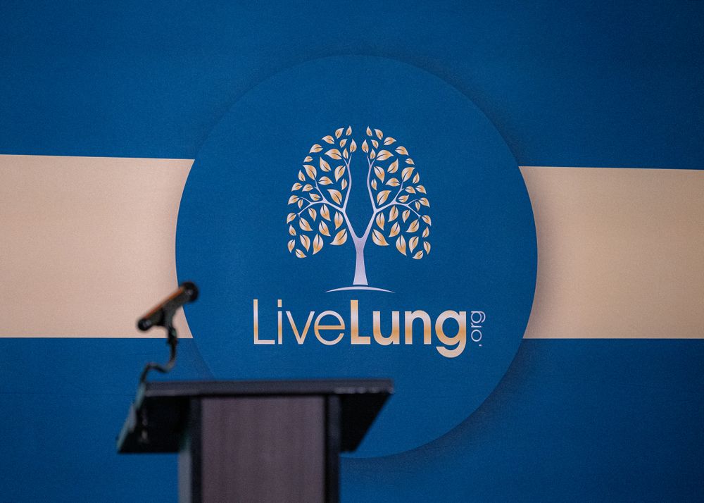 Event speakers stand at a podium with LiveLung branding behind them.