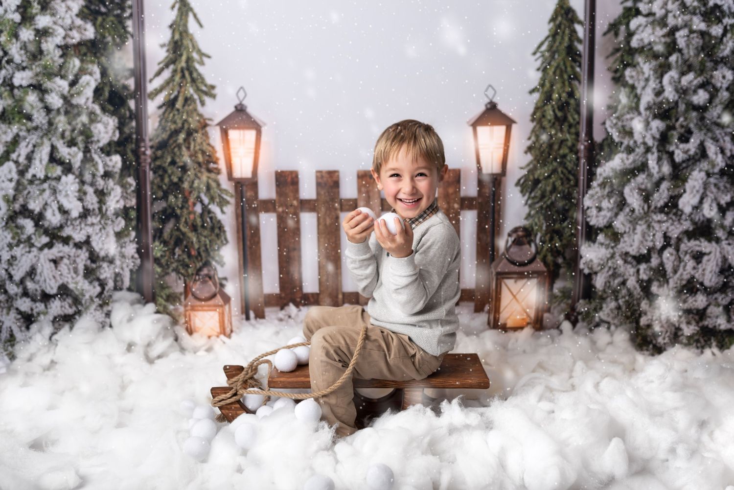 A winter scene with snowy evergreen trees, wooden fencing, glowing lanterns and rustic decorative elements.