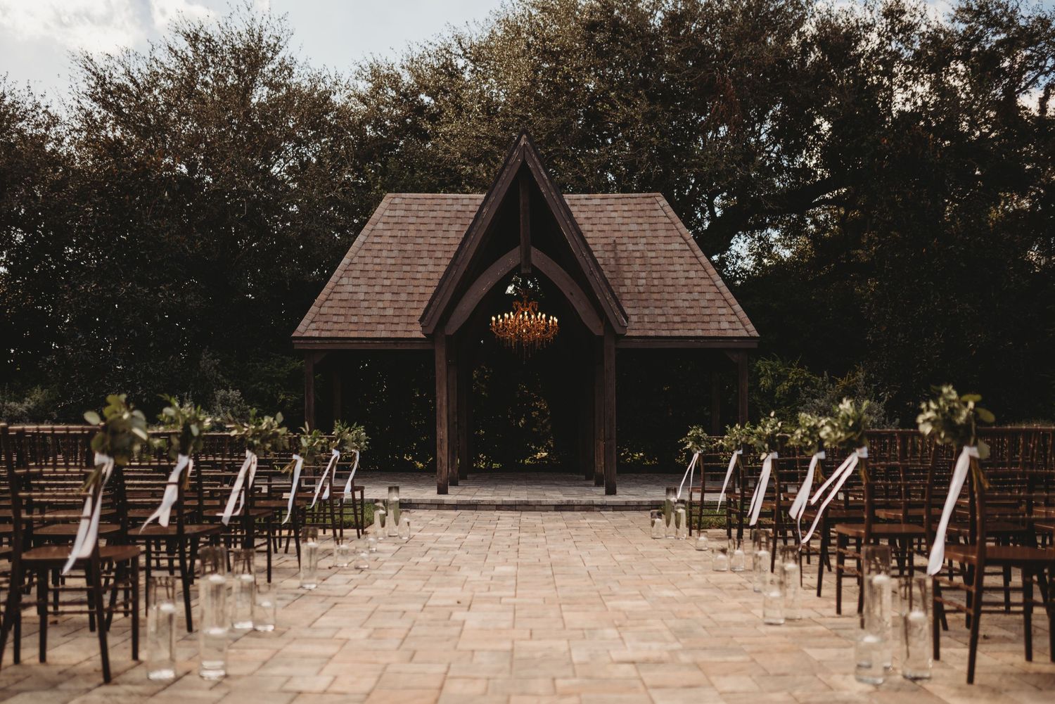 An empty outdoor wedding ceremony setup with wooden chairs leading to a chapel altar.