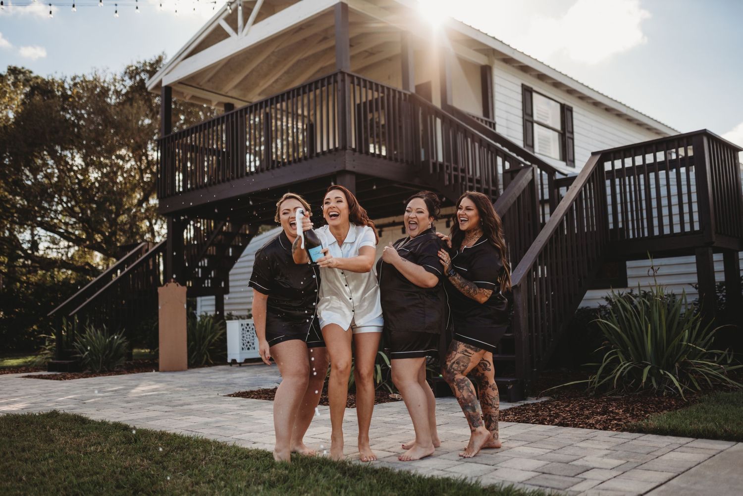Group celebrating outside a house with a deck on a sunny day.