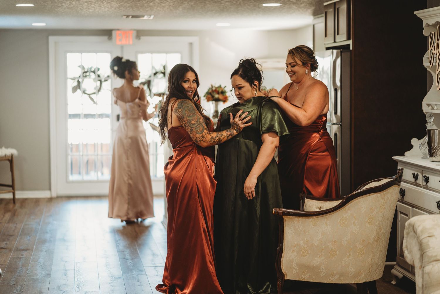 Wedding party helping with dress preparations in an elegant room.