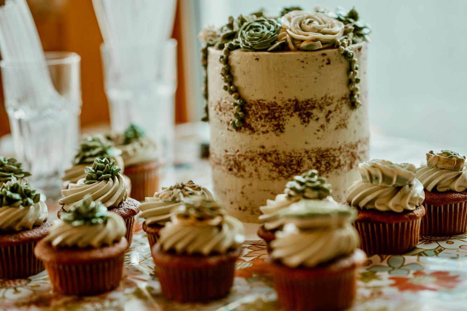 Elegant wedding dessert display featuring naked cake and decorated cupcakes.