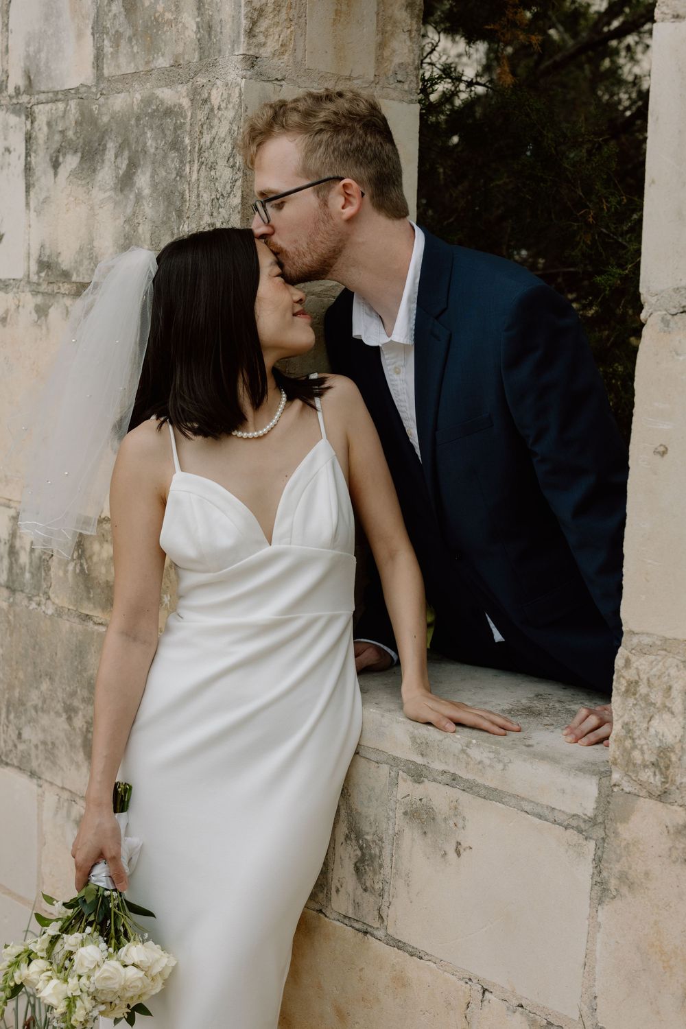 groom kissing bride on forehead
