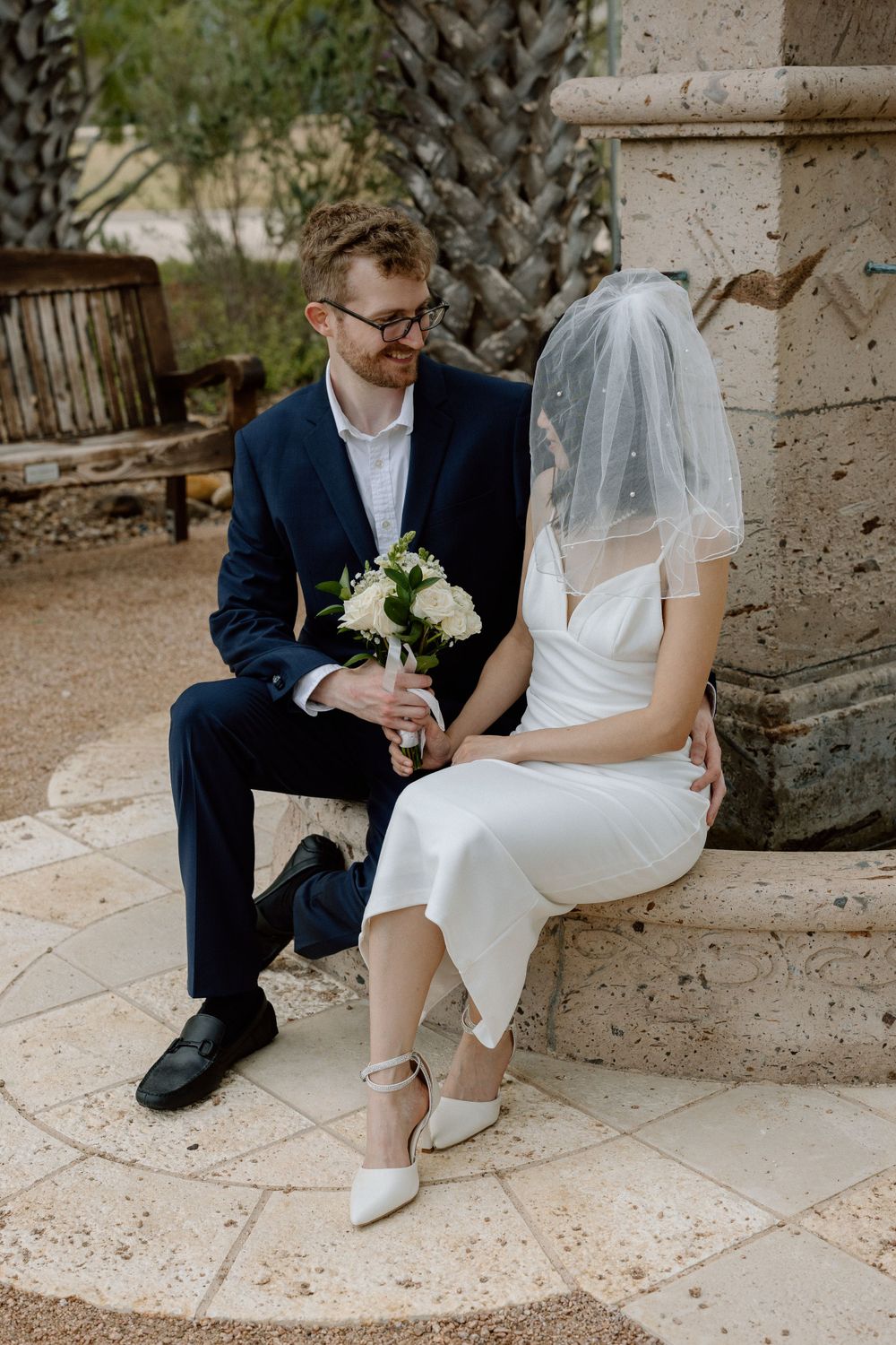 bride and groom sitting on fountain