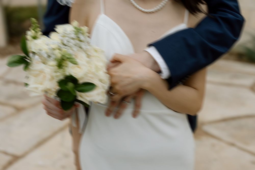 blurry photo of groom's arm wrapped around bride who is holding her bouquet