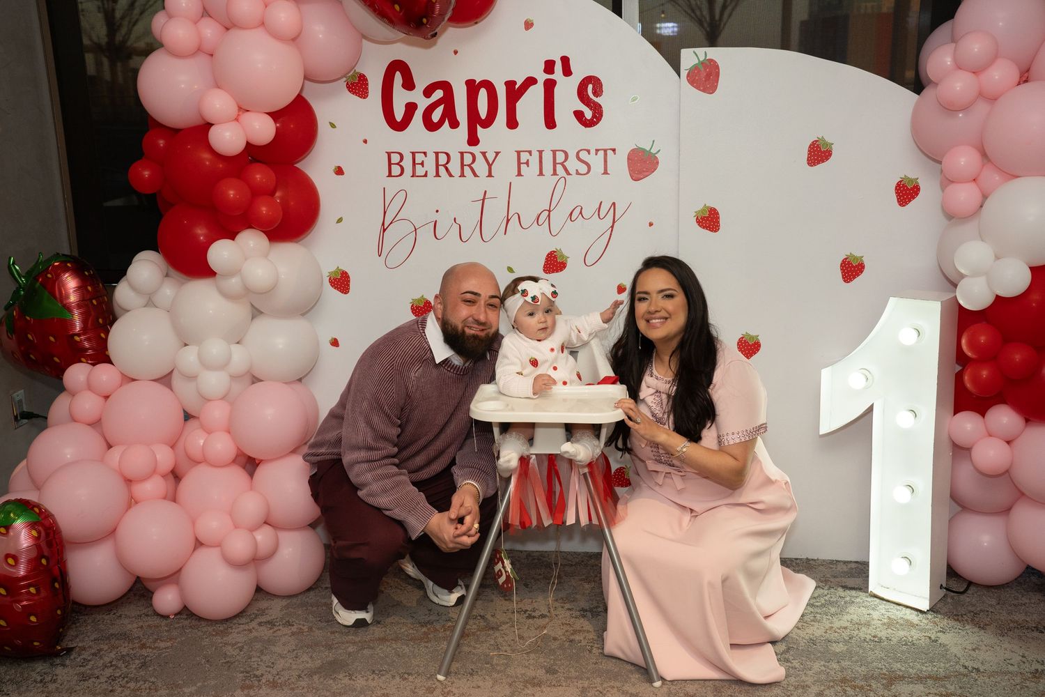 Pink and red balloon decorations with party setup for a first birthday celebration.