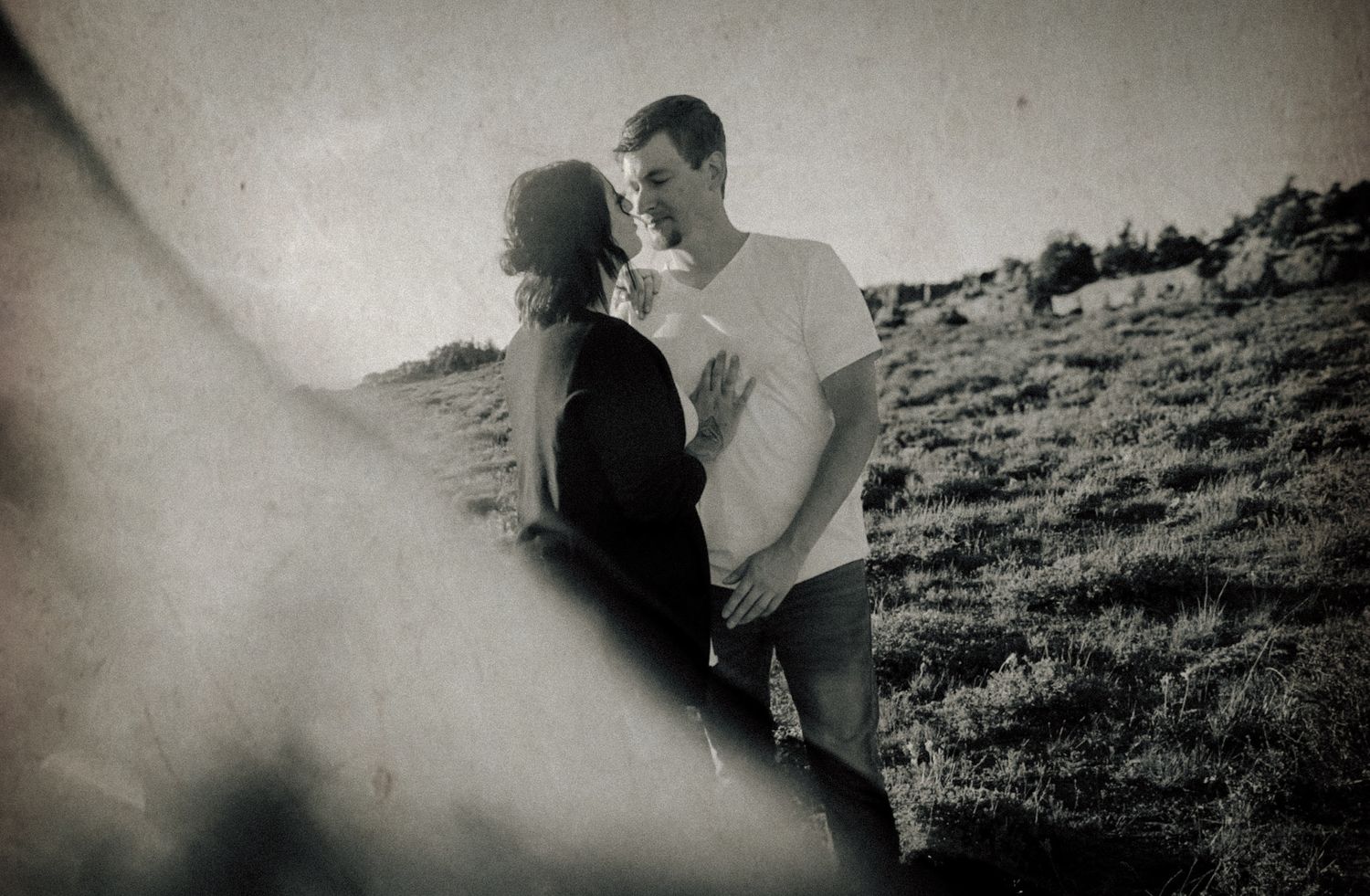 Black and white romantic portrait of couple on hillside in vintage style.