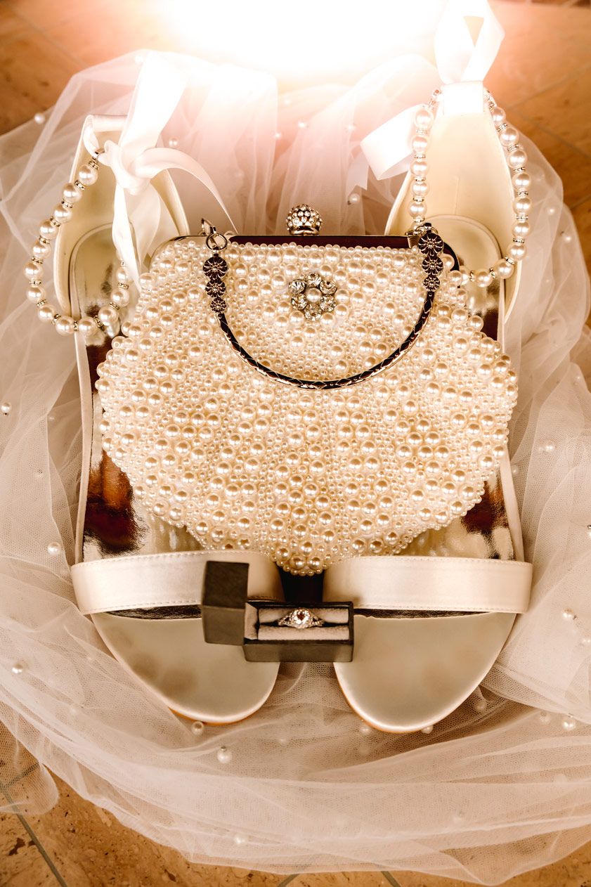 Pearl-encrusted vintage bridal purse displayed with white wedding shoes and veil.