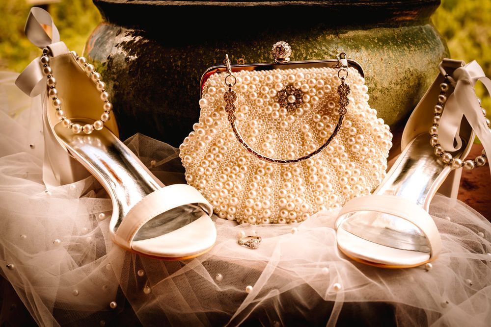 Elegant bridal accessories featuring sparkly gold clutch and white heels with tulle details.