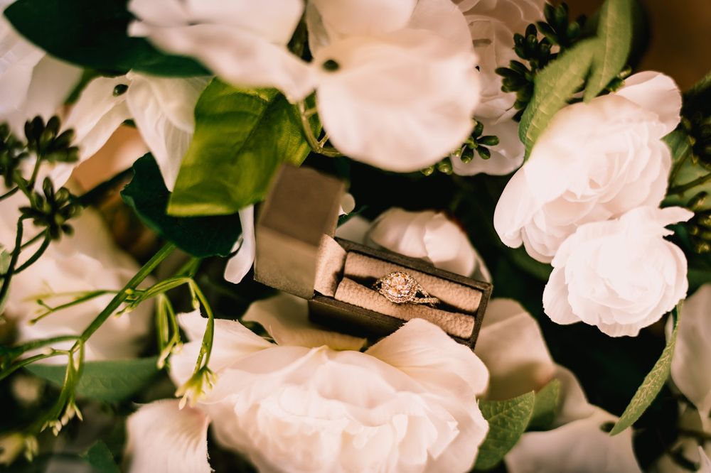 Wedding rings nestled among soft white roses and greenery.