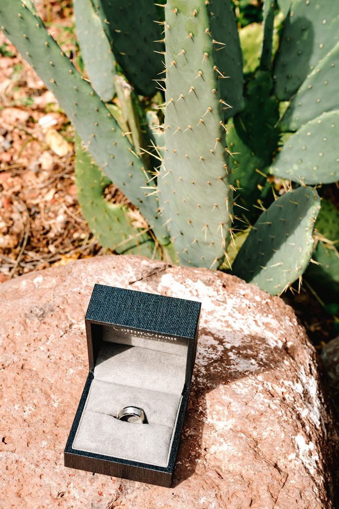 Diamond engagement ring in black box displayed on Sedona rock near desert cactus.