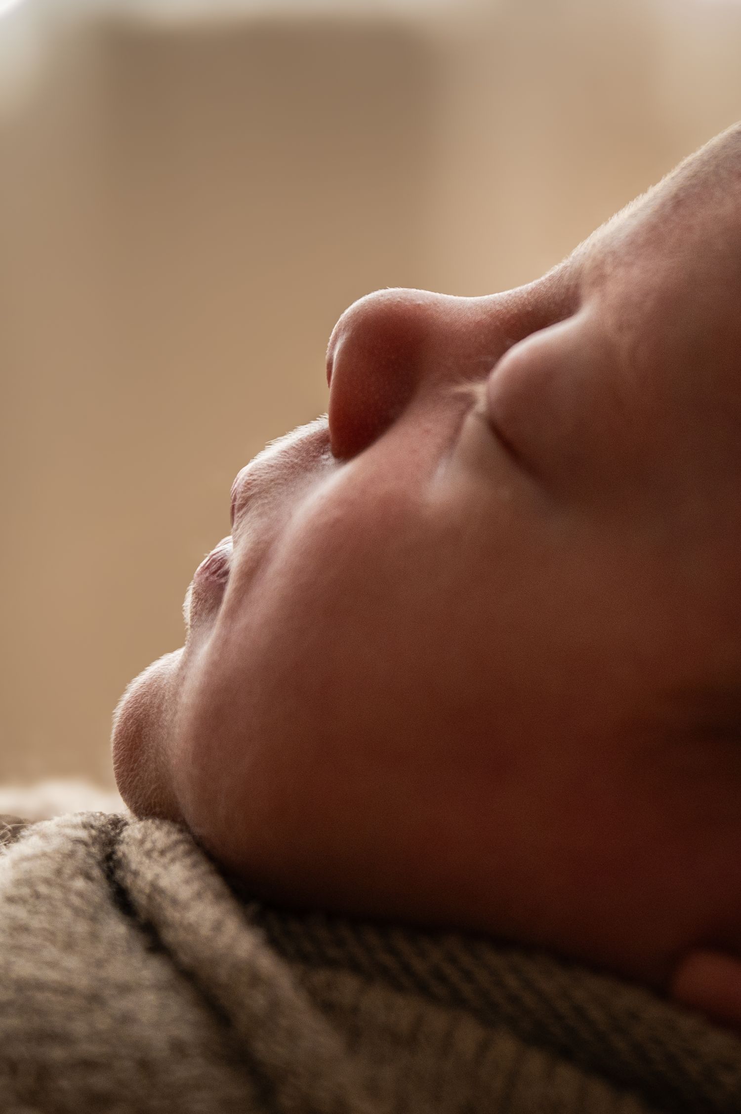 Close-up profile of sleeping baby's face resting on textured fabric.