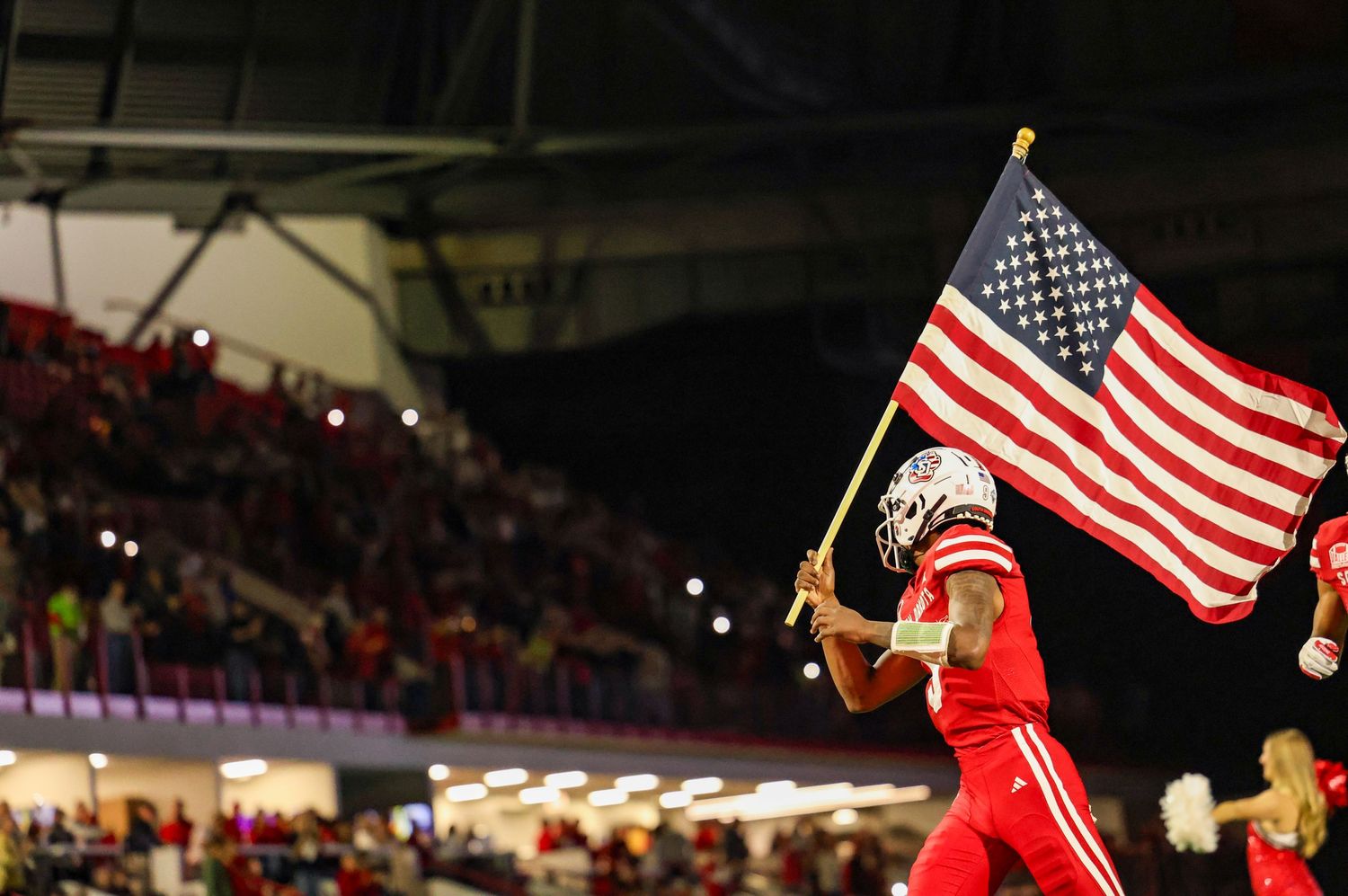 Football player leading his team out on the field while carrying the American flag