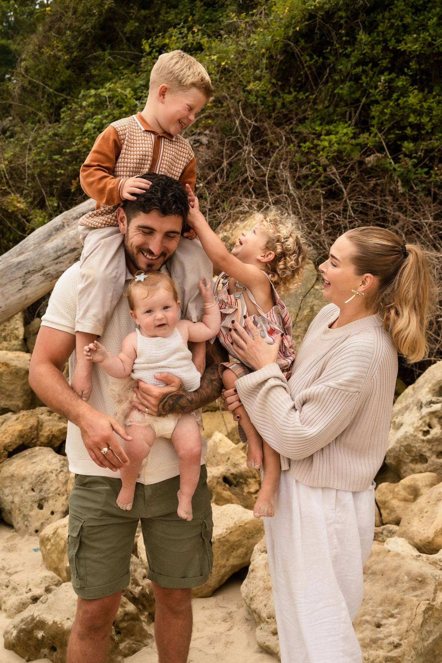 Family sharing joyful moments together on rocky beach terrain.