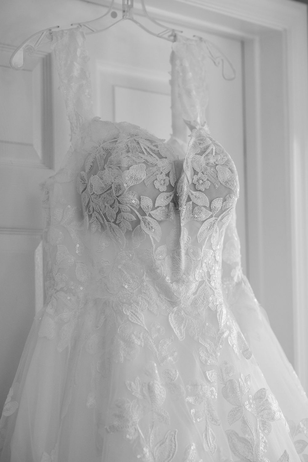 Detailed lace wedding dress with sweetheart neckline hanging on display.