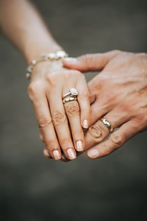 Close-up of hands with wedding rings and a delicate pearl bracelet showing romantic jewelry details.