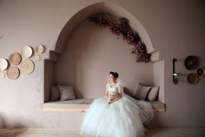 A white wedding dress displayed in a cozy built-in alcove decorated with decorative plates on the wall.
