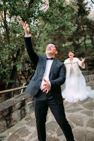 A joyful moment captured as someone tosses something in the air during an outdoor wedding.