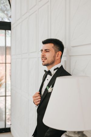 A classic black tuxedo captured in an elegant white interior setting with window light.