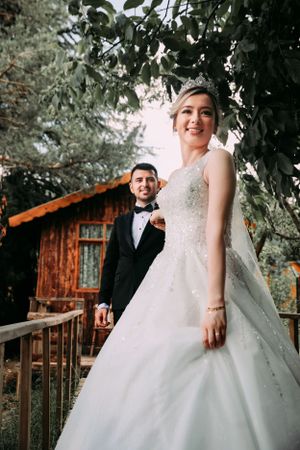 A wedding photo taken outside a rustic wooden cabin with natural greenery.