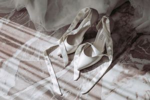 White bridal heels with elegant straps laid out on a textured surface.