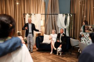 Wedding party relaxing in elegant room with gold curtains and formal attire.
