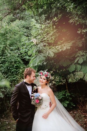 Romantic garden wedding portrait with couple surrounded by lush greenery.