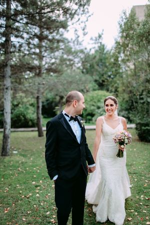 Wedding couple sharing a moment on grass surrounded by pine trees.