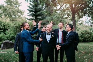 Groomsmen celebrating and cheering outdoors during wedding festivities.