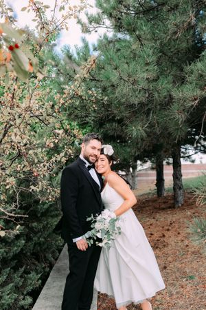 Romantic wedding portrait among pine trees and spring blossoms.