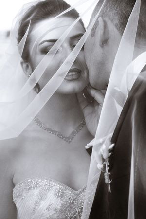 Artistic black and white wedding portrait through delicate veil fabric.