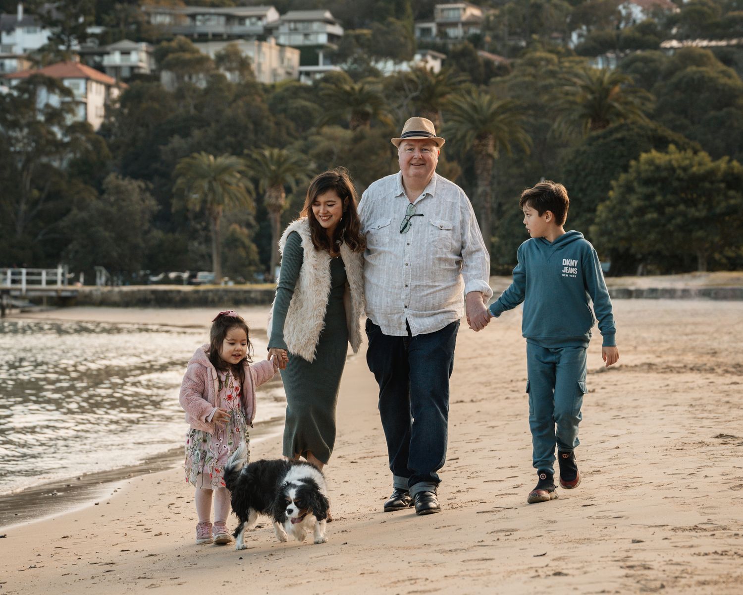 family-walking-on-the-beach-towards-the-camera-with-their-dog-in-mosman