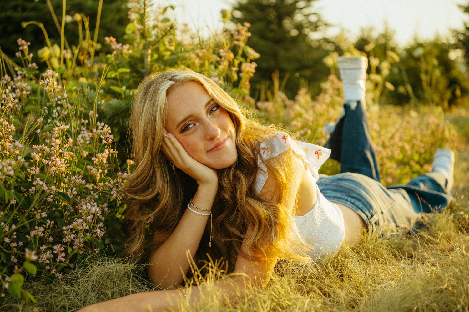 Sunny outdoor portrait of someone lying in wildflower meadow wearing yellow and white.