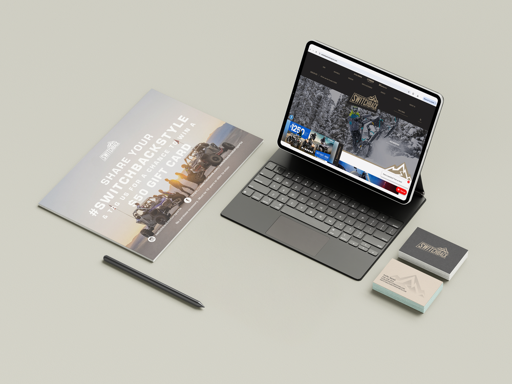 Modern Surface tablet with keyboard cover displaying a website, alongside a notebook, stylus pen and business card on gray desk.