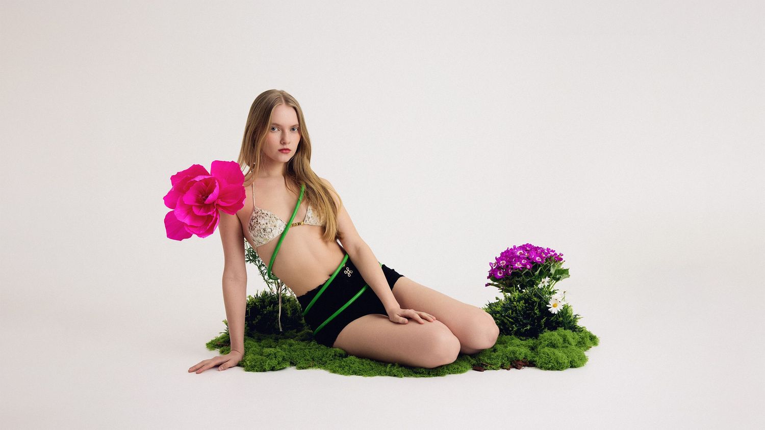 A maternity photo shoot with floral elements against a white backdrop.