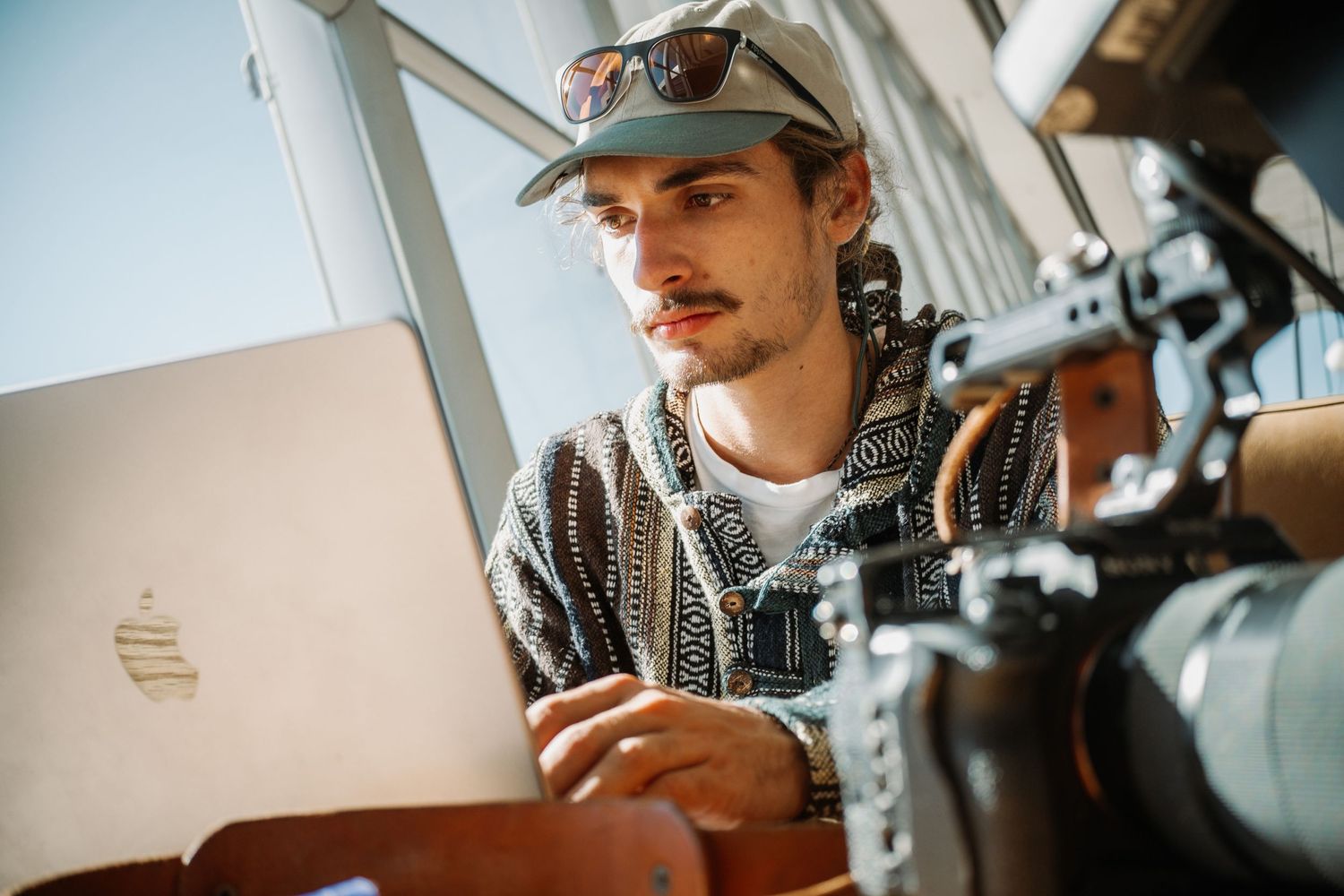 Content creator working on laptop with camera equipment while aboard fishing vessel.