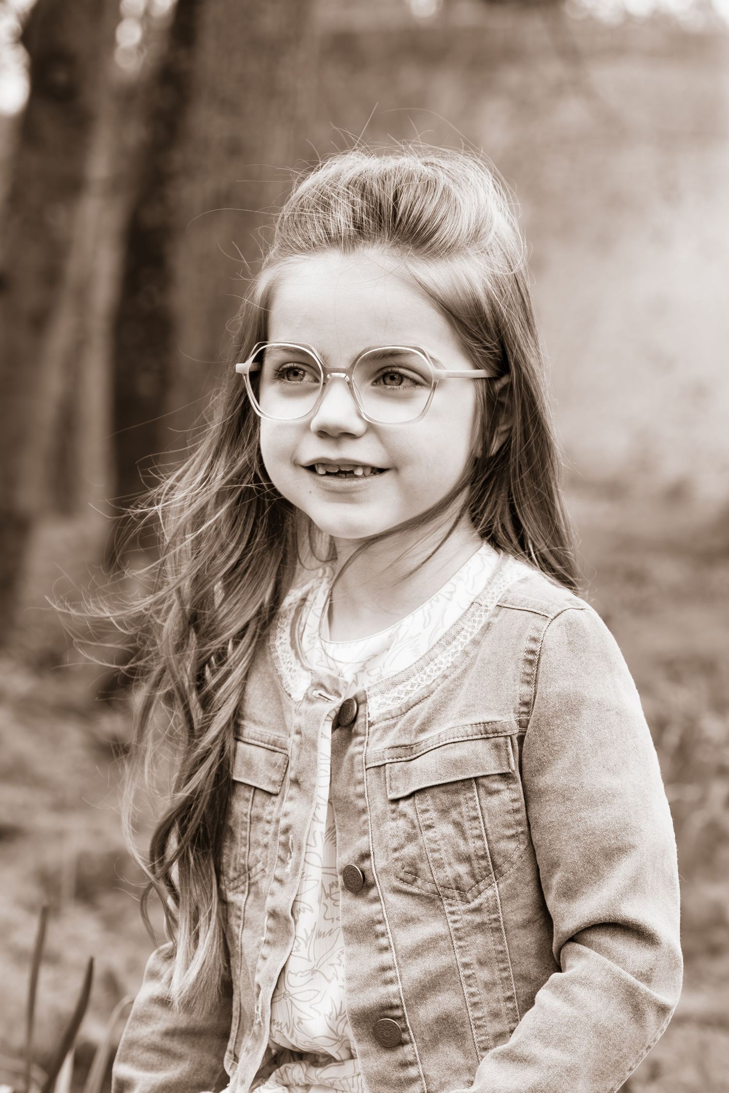 Vintage style portrait of young person wearing glasses and denim jacket.